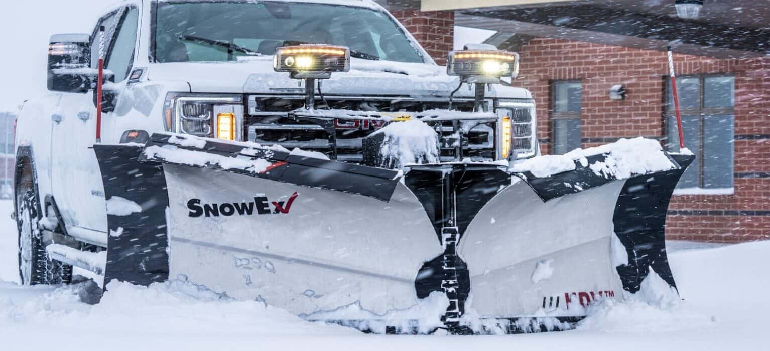 white truck with snow plow in snowy weather
