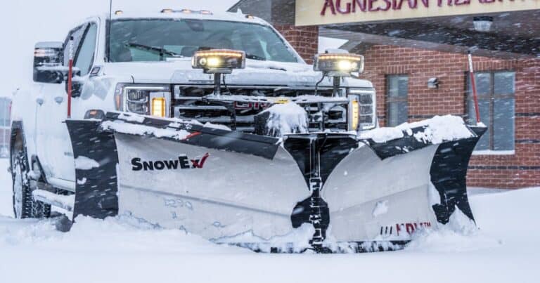white truck with snow plow in snowy weather