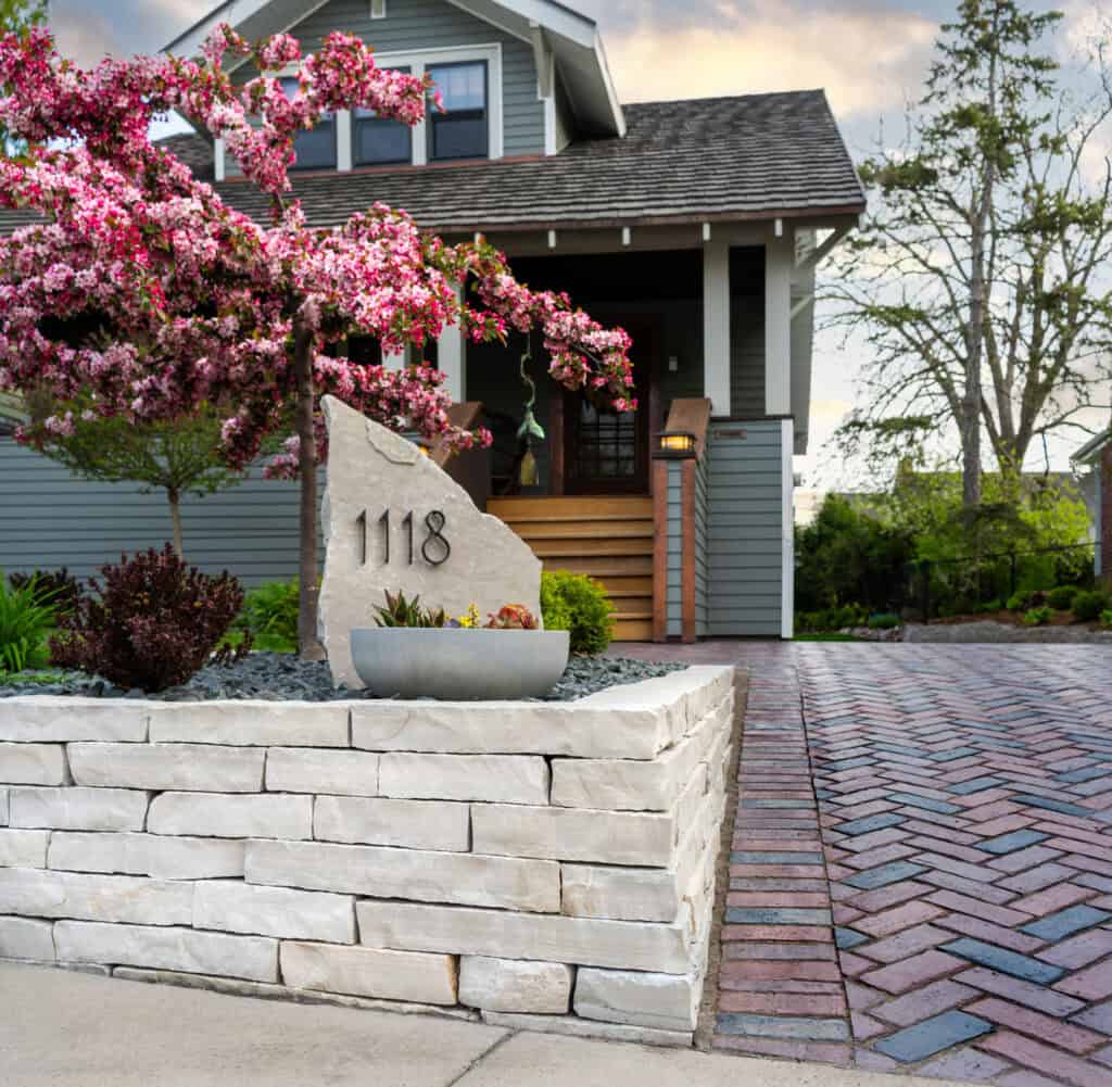 Front yard with flowering tree, stone wall, and address boulder in Oshkosh, WI
